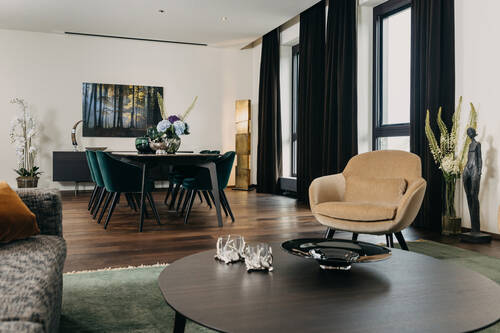 Wohn- und Essbereich des Penthouses mit Tischen und Sitzgelegenheiten.