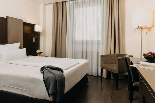 Aufnahme des Cozy Zimmers mit Bett, Schreibtisch und Sitzgelegenheit.