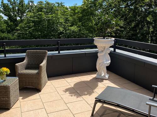 Sonniger Balkon mit Liege und Sitzgelegenheiten sowie Pflanzen.