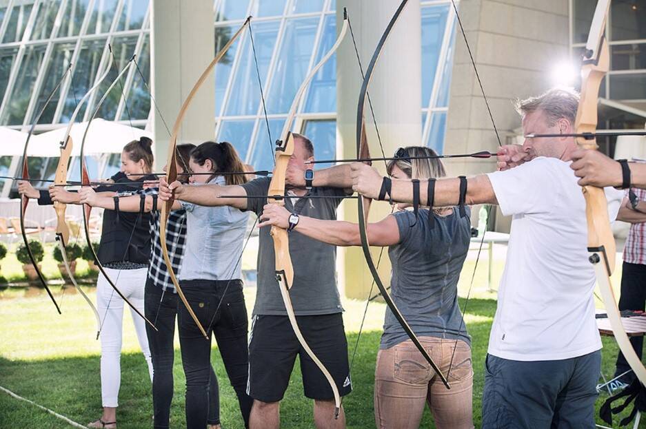 Several people who practice archery and have bows strung.