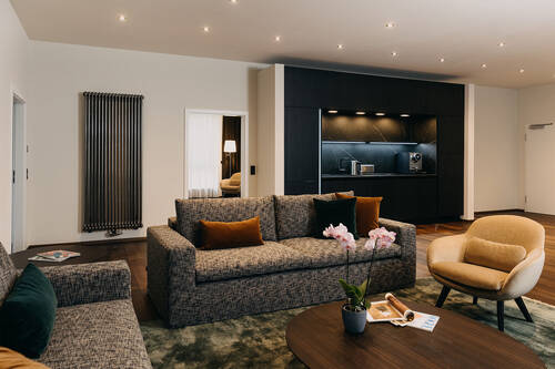 Wohnbereich einer Hotelsuite mit Sofas und Küche im Hintergrund.