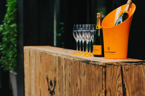 Champagnergläser und Flaschen sowie ein Eiskühler von Veuve Cliquot.