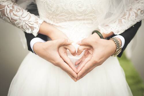 Ein Herz formende Hände von einem Hochzeitspaar.
