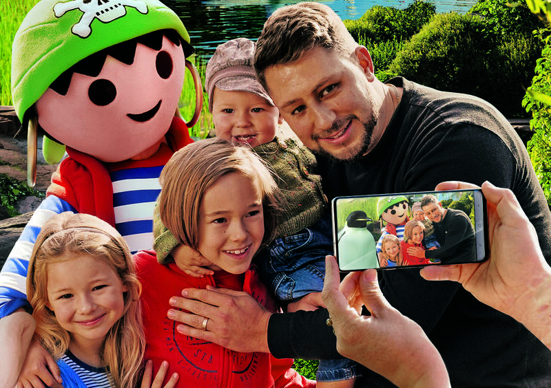 Eine Familie macht mit einem Maskottchen ein Foto.