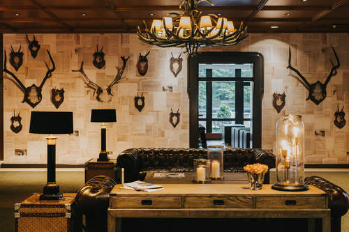 Lobby Forsthaus Fürth mit Ledersofas, Tisch und Dekoration.