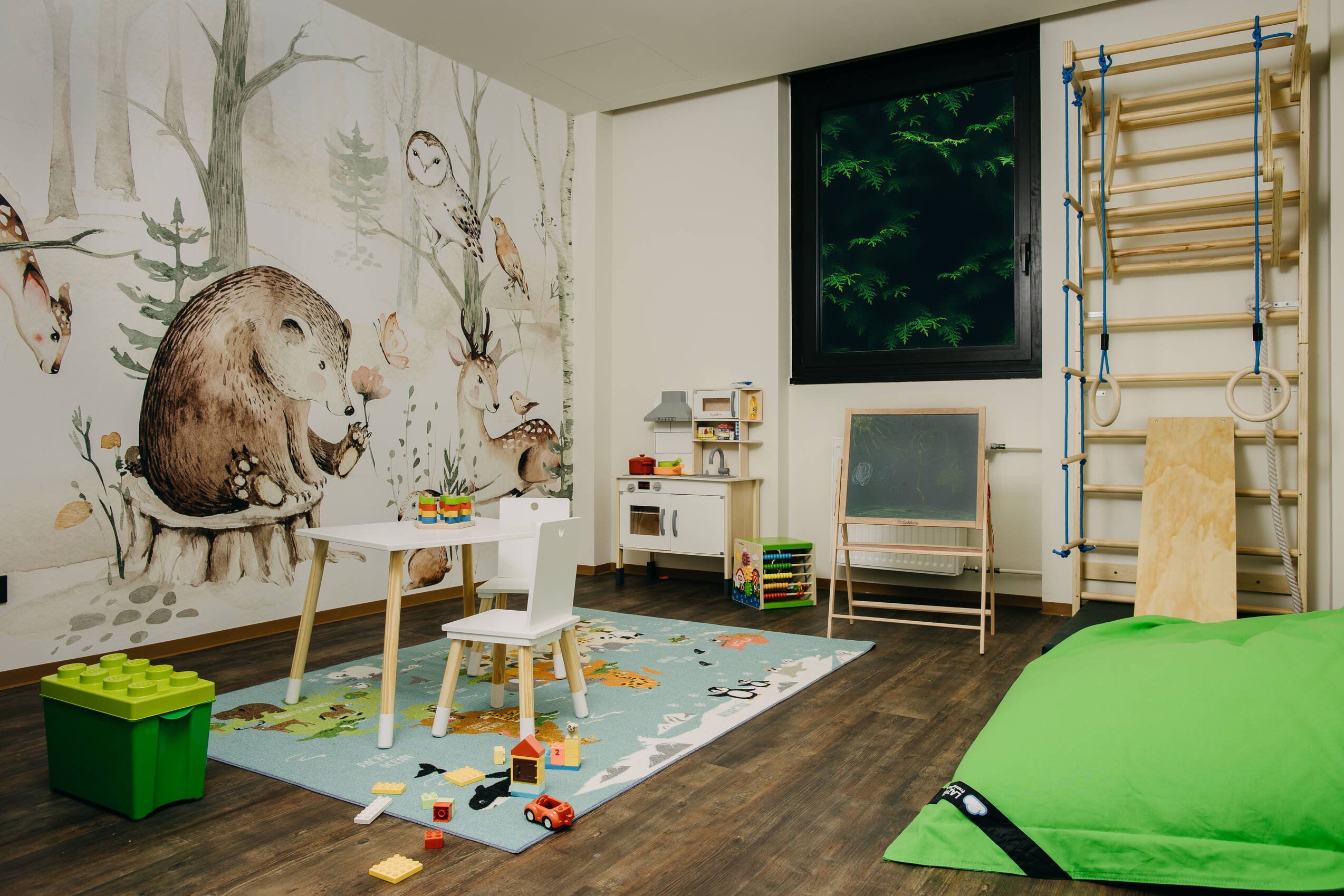 Spielzimmer mit bunter Tapete und verschiedenen Spielmöglichkeiten für Kinder.