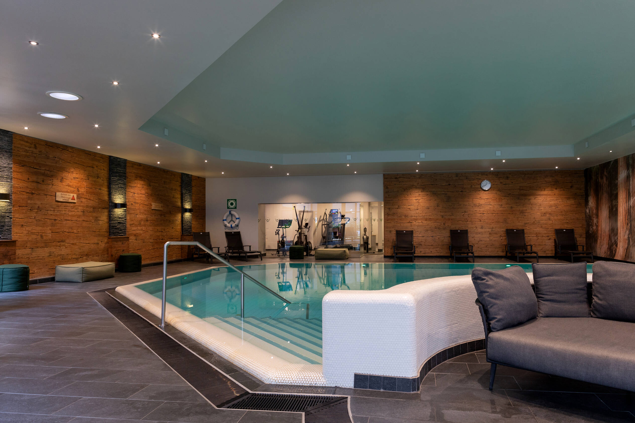 Indoor-Pool mit Loungemöbeln und Liegen.
